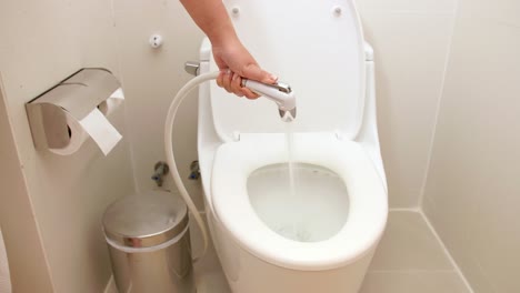 Eine-Frau-Benutzt-Einen-Schlauch,-Um-Wasser-In-Der-Toilette-Zu-Spülen,-Um-Es-Zu-Reinigen