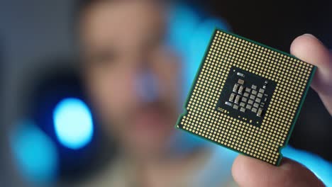 Male-technician-holds-in-hand-CPU-processor,-Integrated-circuits-microchips-concept,-Blurred-background