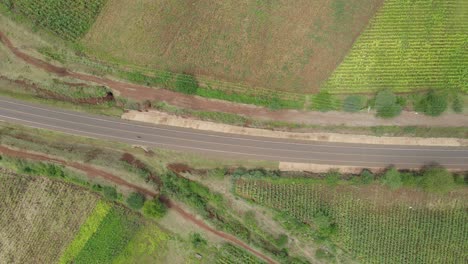 Top-down-view-on-single-motorcycle-driving-countryside-road,-Loitokitok,-Kenya