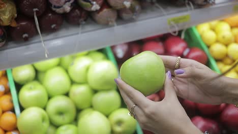 Chica-En-El-Supermercado-Tomando-Manzanas-Verdes