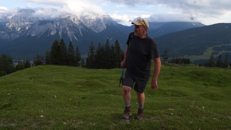Man-walking-up-grass-hill-mountain-in-the-Austrian-Alps-peak