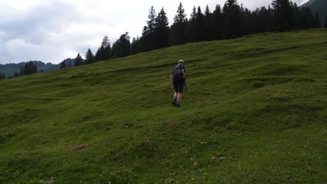 Man-walking-up-grass-hill-mountain-Austrian-Alps