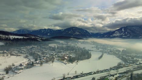 Aerial-shot-of-a-snow-covered-mountain-town-in-fog