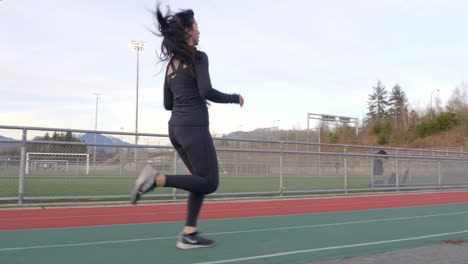 Toma-De-Seguimiento-De-La-Vista-Trasera-De-Una-Mujer-Asiática-Corriendo-En-Una-Pista-De-Atletismo