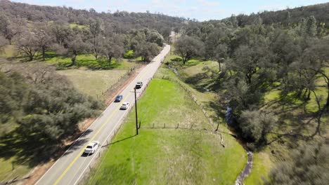 drone-following-car-drive-through-a-oak-forest-in-rolling-hills