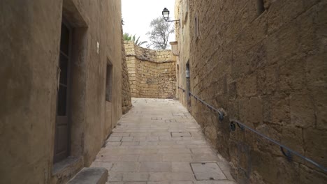 Walking-in-Narrow-Coblestone-Cittadella-Street-With-Iron-Handrail-on-Wall-in-Gozo-Island