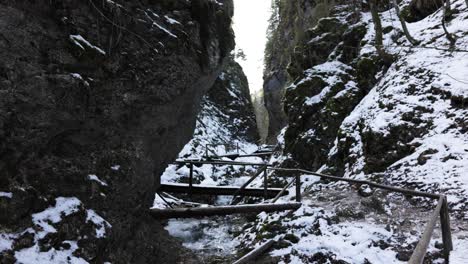 Holzbrücke-Zwischen-Schroffen-Klippen,-Die-Im-Winter-Mit-Schnee-Bedeckt-Sind
