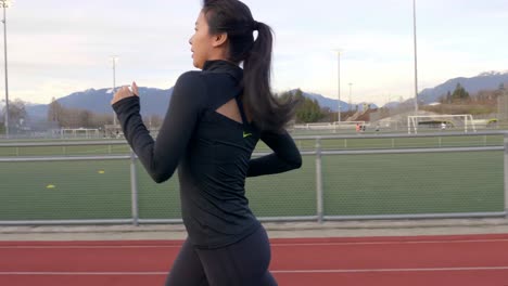 Close-up-tracking-shot-of-Asian-woman-running-on-athletics-track