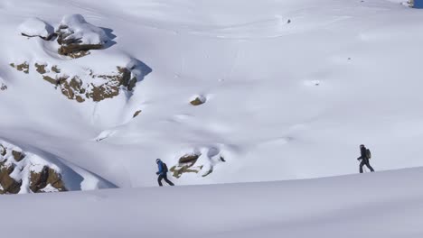 Hikers-snowshoeing-in-deep-snow-of-the-Alps-of-Tyrol,-bright,-winter-day-in-Austria---pan-shot