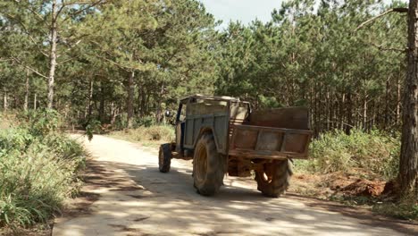 Panning-motion-follow-old-rusty-truck-on-rural-pathway,-Persimmon-plantation-farm,-Vietnam