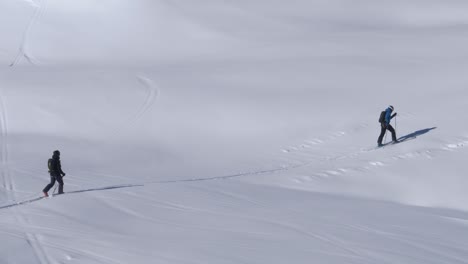 Skiers-trekking-in-deep,-natural-snow,-untouched-trails-high-altitude-in-the-Alps---Handheld-view