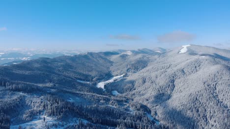 Vista-Of-Dense-Woodland-On-Snow-Mountains-During-Winter-Season