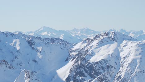 Lines-of-snowy-Alpine-massif,-full-of-rocky-peaks,-sunny,-winter-day-in-the-Alps--pan-shot