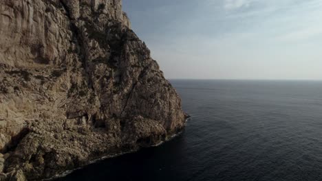 Aerial-shot-of-the-massive-cliffs-and-a-dark-calm-Mediterranean-sea-surface