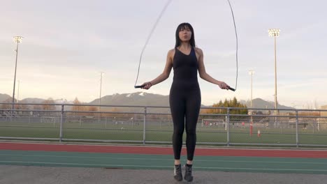 Gimbal-Low-Angle-Shot-Einer-Asiatischen-Frau,-Die-Draußen-Seil-Springt