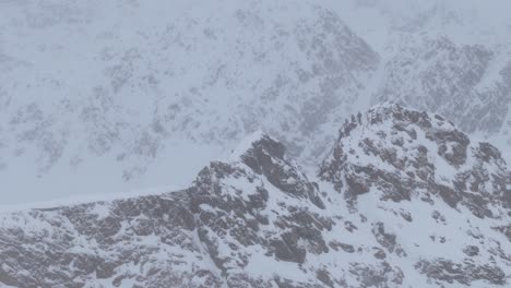 Details-of-rocky-cliffs-in-a-snowstorm,-high-in-the-alps-of-Tyrol---pan-view