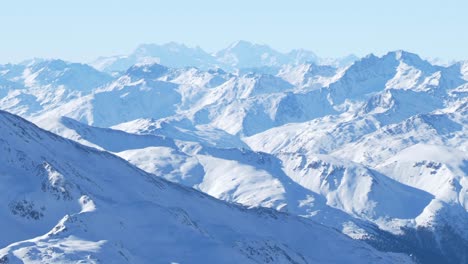 Endless-view-of-snowy-peaks-and-ridges,-bright-winter-day-in-Tyrol---pan-shot