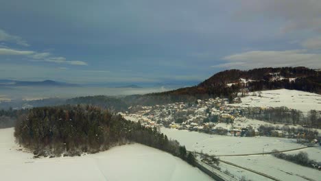 Aerial-shot-of-a-snow-covered-mountain-town-in-fog