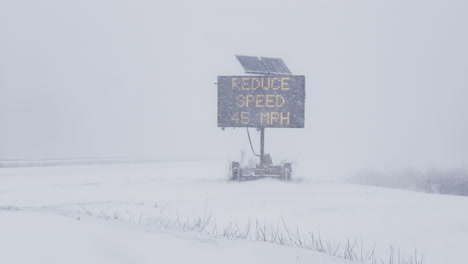Reduce-speed-road-sign-warning-during-whiteout-blizzard-on-I-295-in-Freeport,-Maine