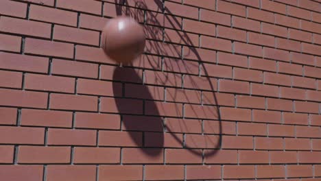 Slow-motion-shot-of-basketball-net-silhouette-shadow-as-ball-goes-into-ring-scoring-goal-on-red-brickwork-wall