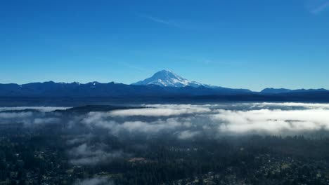 Vista-Pintoresca-Del-Majestuoso-Monte-Rainier-En-El-Estado-De-Washington-Con-Nubes-Bajas-Sobre-Los-árboles-En-Primer-Plano