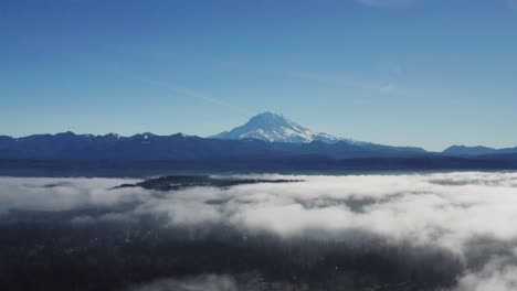 Vista-Aérea-Del-Famoso-Monte-Rainier-Con-Nubes-Sobre-Bosque-Verde-En-El-Estado-De-Washington,-EE.UU.