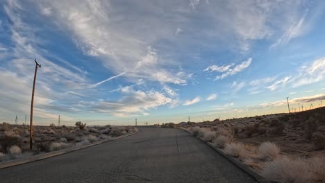 A-road-leading-to-a-Mojave-Desert-highway-with-wispy-clouds-overhead---cloudscape-time-lapse