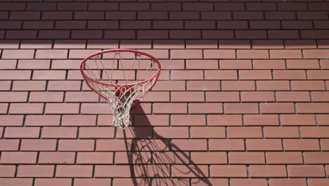 Frontschuss-Des-Basketballs,-Der-Auf-Rotem-Backsteinmauerhintergrund-Ins-Netz-Geht,-Um-Ein-Tor-Zu-Erzielen