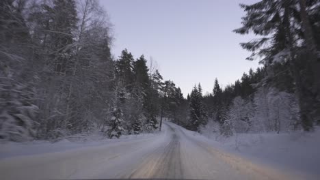 Punto-De-Vista-De-La-Conducción-De-Automóviles-En-Un-Camino-Nevado-En-El-Bosque-De-Invierno