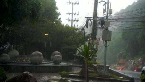 Ein-Gewaltiger-Regenguss-In-Der-Regenzeit-In-Thailand-Erzeugt-Große-Pfützen-Auf-Dem-Boden,-Während-Ein-Roller-Auf-Der-Straße-Fährt