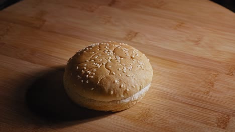 Hand-Legt-Burgerbrötchen-Mit-Sesamsamen-Auf-Holzbrett