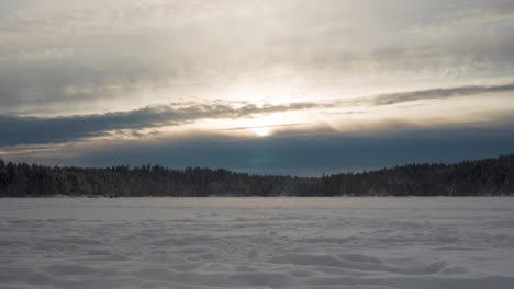 Distant-View-Of-People-Walking-On-Frozen-Lake-With-Dense-Forest-During-Sunset