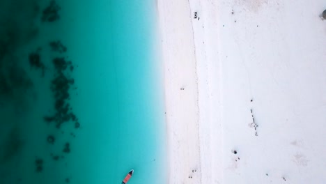 Smooth-aerial-flight-bird's-eye-view-top-drone-shot-over-white-sand-blue-water-wave-and-people