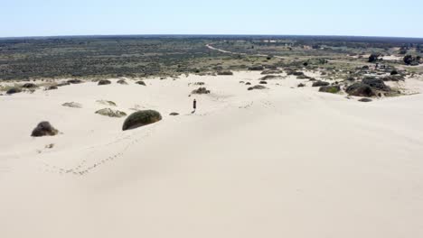 Girl-exploring-huge-sand-dunes-in-an-Australian-desert-on-a-hot-bright-sunny-day,-aerial-shot-3
