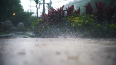Große-Regentropfen-Fallen-Vom-Himmel-Auf-Die-Straße,-In-Der-Bei-Einem-Heftigen-Regenschauer-In-Thailand-Mehrere-Wassertropfen-Aus-Der-Regenpfütze-Aufsteigen