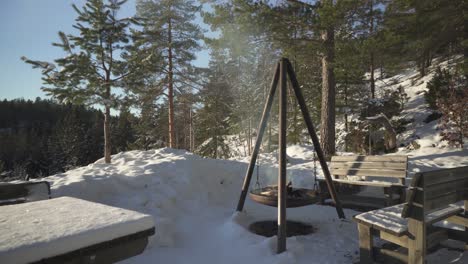 Holzverbrennung-Im-Dreibeinigen-Hängegrill-Vor-Der-Hütte-Im-Winter