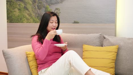 Schöne-Asiatische-Frauen-Ruhen-Sich-Auf-Dem-Sofa-Aus-Und-Trinken-Kaffee-In-Der-Morgendlichen-Urlaubszeit