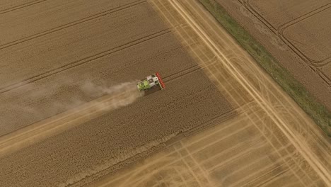 Harvest-drone-pivot-around-combine-harvester-in-field-at-mid-to-high-altitude