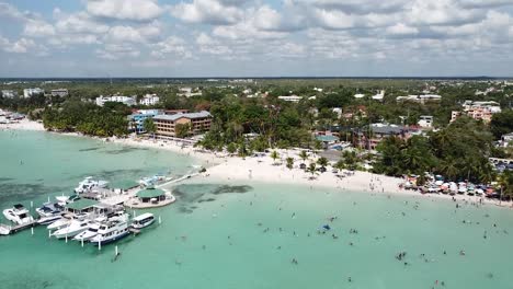 drone-shot-approaching-beautiful-tropical-beach-of-boca-chica-in-dominican-republic,-sunny-day-with-beautiful-boats-at-the-marina