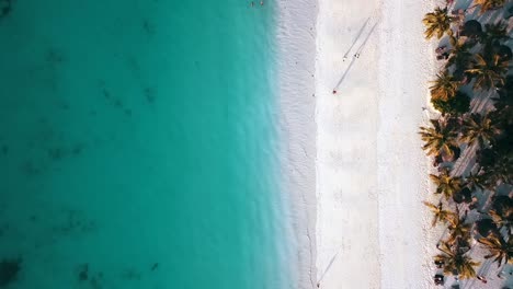 1-million-$-aerial-flight-bird's-eye-view-drone-shot-of-people-walking-with-long-shadows-on-white-sand-paradise-dream-beach-Zanzibar,-Africa-Tanzania-2019-Cinematic-nature-1080,-60p-by-Philipp-Marnitz