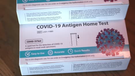 Covid-19-at-home-Antigen-test-kit-for-coronavirus-3-white-and-blue-boxes-of-tests-stacked-up-close-wide-shot-focusing-on-bottom-box-and-slowly-twisting