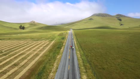 Gente-En-Bicicleta-Por-Una-Carretera-Asfaltada-Con-Paisaje-De-Campo-Verde-En-San-Luis-Obispo,-California