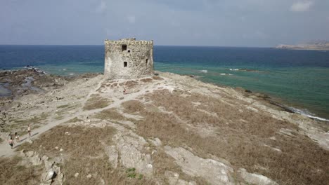 Aerial-fast-approach-to-the-La-Pelosa-watchtower-built-in-the-XVI-century-on-a-small-rocky-island