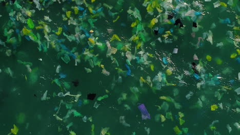 Endless-number-of-disposable-plastic-bags-floating-in-ocean-waves,-aerial-top-down-ascend-shot