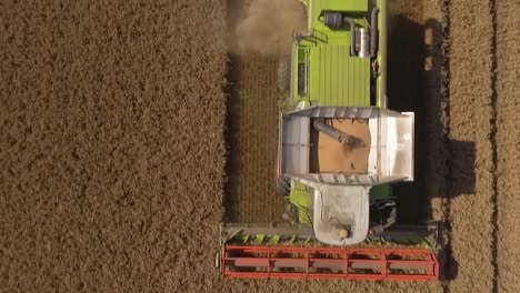 Harvest-drone-flies-close-over-crop-dust-then-Claas-combine-harvester