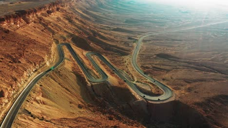 Several-cars-descend-on-the-black-asphalt-with-hairpin-bends-on-the-highway-40-in-Mitzpe-Ramon-in-Israel-in-the-beautiful-brown-hill-landscape