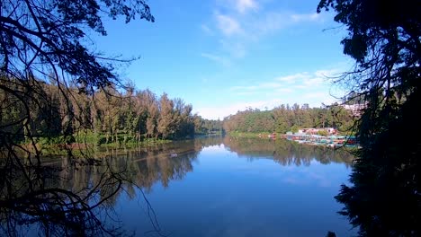 pristine-calm-water-lake-with-reflection-of-soothing-blue-sky-and-surrounded-by-green-forests-video-taken-at-ooty-lake-tamilnadu-india