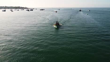 Fleet-of-Vietnamese-fishing-boat-heading-home-after-fishing-trip-in-Mui-Ne,-aerial-view
