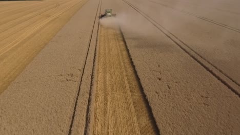 Harvest-drone-pullback-behind-combine-harvester-in-field,-crop-dust