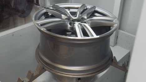 The-aluminium-wheel-is-finished-cutting-to-repair-a-curb-rash,-is-lifted-out-of-the-cabinet-in-4k